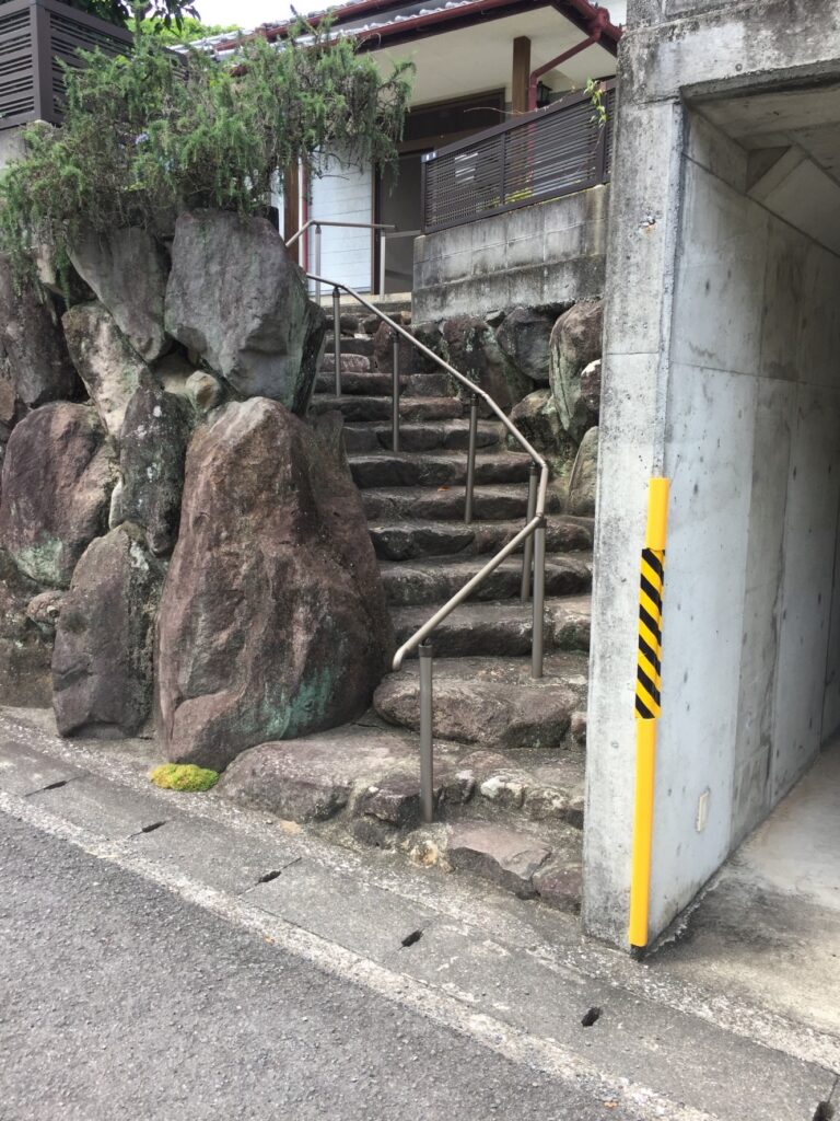 着工前の自然石階段の全景。高さ約3メートルの石垣に、大小不揃いの自然石が階段状に積まれている状態