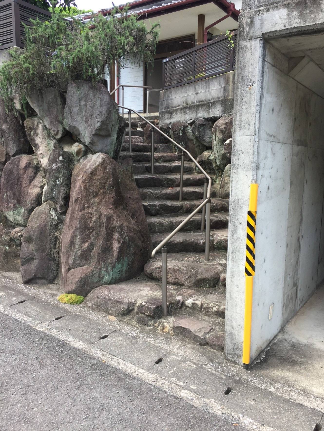 着工前の自然石階段の全景。高さ約3メートルの石垣に、大小不揃いの自然石が階段状に積まれている状態