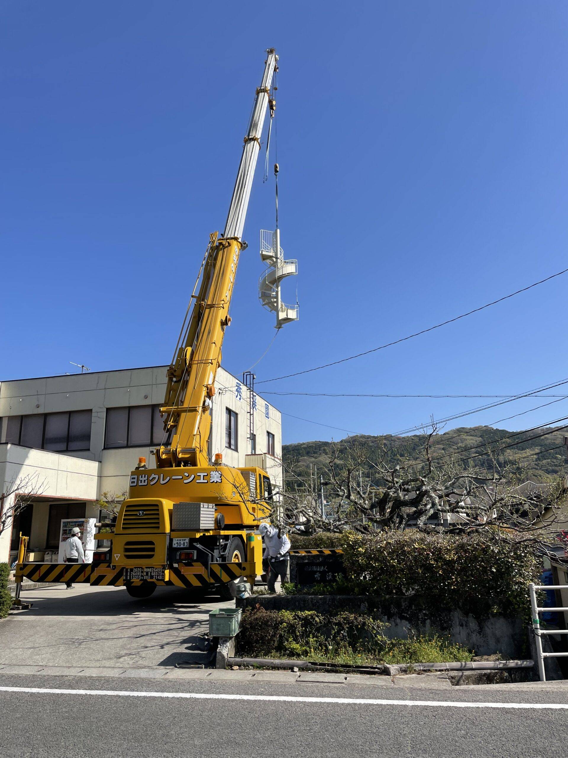 非常用滑り台。クレーンで持上げ。設置作業中。