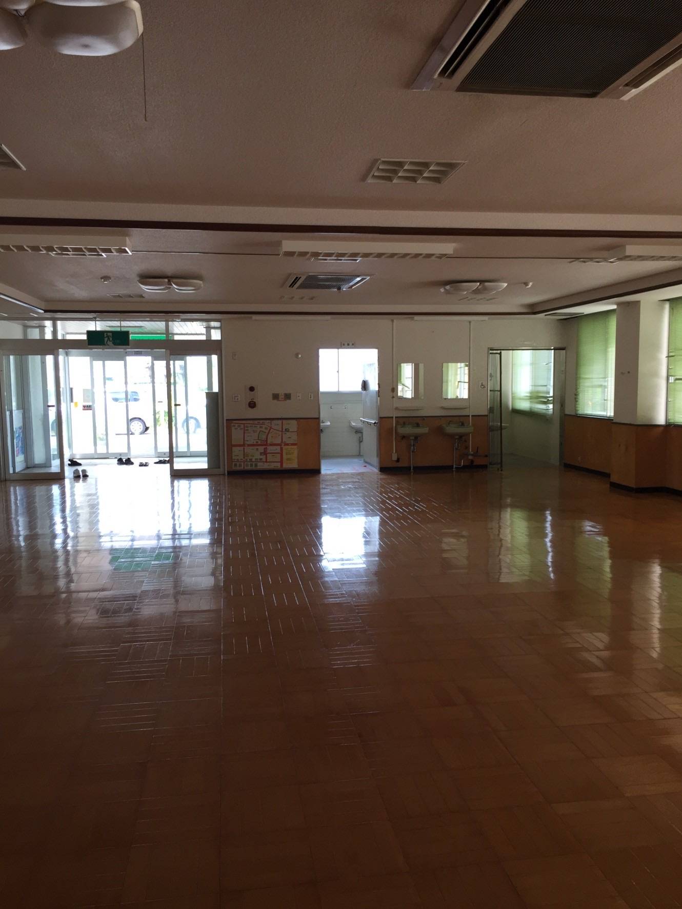 張り替え前のホールの壁紙とブラインド。色あせや傷が目立つ状態。